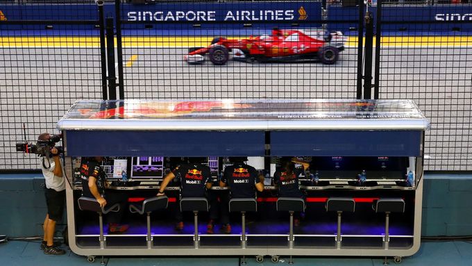 Sebastian Vettel ve Ferrari projíždí před boxy Red Bullu na okruhu v Singapuru.