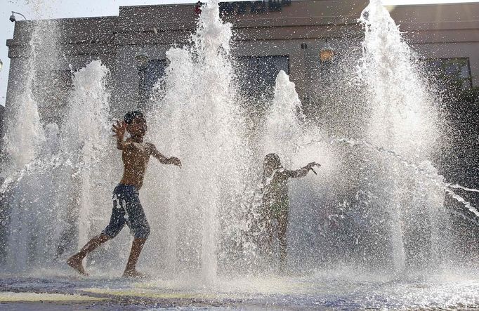 Children play in a water fountain in downtown Silver Spring, Maryland June 21, 2012. A heat wave blanketed the U.S. Mid-Atlantic and Northeast on Thursday, forcing utilities across the region to ask customers to conserve electricity. REUTERS/Jose Luis Magana (UNITED STATES - Tags: ENVIRONMENT ENERGY SOCIETY) Published: Čer. 21, 2012, 10:47 odp.