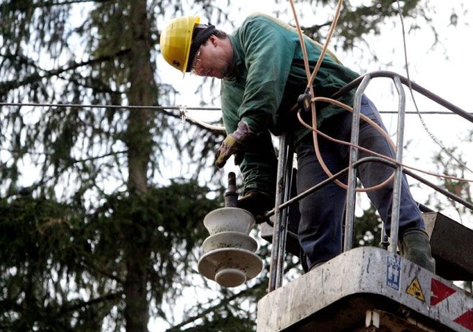 Elektrikář háže na zem poškozený izolátor po noční vichřici.