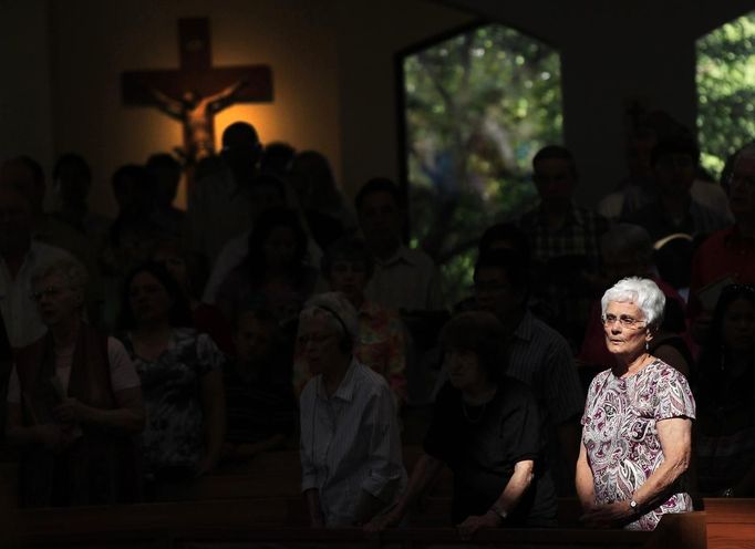 A woman stands during a morning mass remembering the victims of the movie theatre shootings, at the Queen of Peace Catholic Church in Aurora, Colorado July 22, 2012. President Barack Obama travels to Colorado on Sunday to meet families bereaved after a "demonic" gunman went on a shooting rampage at a movie theater in a Denver suburb, killing at least 12 people and wounding 58. REUTERS/Shannon Stapleton (UNITED STATES - Tags: DISASTER SOCIETY CIVIL UNREST RELIGION) Published: Čec. 22, 2012, 4:49 odp.