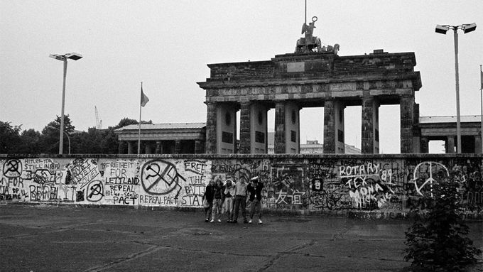 Archivní snímek zachytil turisty pózující před Berlínskou zdí u Braniborské brány v červnu 1989.