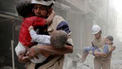 Záchranáři vynášejí děti z rozbombardovaných domů ve východním Aleppu.