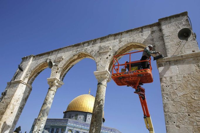 The Dome of the Rock is seen in the background as a Palestinian labourer repairs a light on a wall during preparations ahead of the holy month of Ramadan on the compound known to Muslims as "al-Haram al-Sharif" and to Jews as "Temple Mount" in Jerusalem's Old City July 8, 2013. REUTERS/Ammar Awad (JERUSALEM - Tags: RELIGION) Published: Čec. 8, 2013, 1:04 odp.