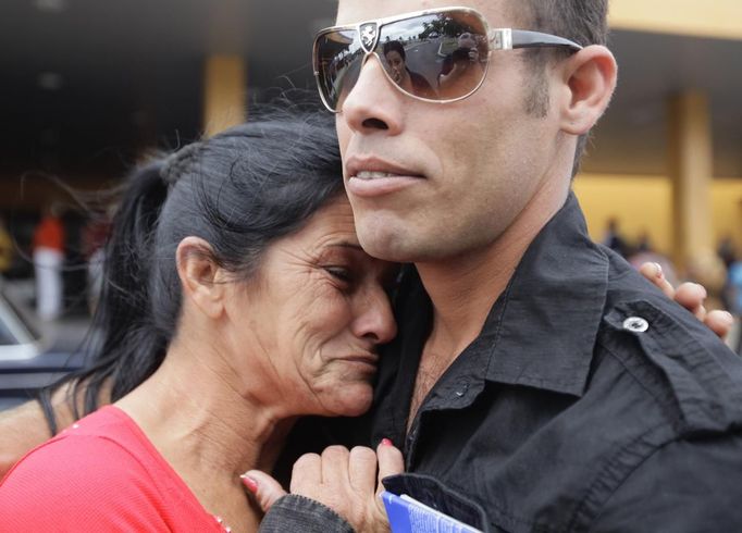 Niurka Gonzalez (L), cries while saying goodbye to her son Luis Salgado, nicknamed Chucho, as he prepares to board a flight to Miami, outside the Havana airport terminal March 13, 2013. Chucho was granted a U.S. visa based on his father's status as legal resident in Texas, and he was reunited in Miami with his father, Jesus Salgado, who had escaped Cuba on a frail boat ten years earlier. The Salgados are among many Cubans taking advantage of Cuba's new travel policy in place since last January, which allows citizens to leave the country with just a passport and no need for much-hated exit visas required since 1961. Picture taken March 13, 2013. REUTERS/Desmond Boylan (CUBA - Tags: POLITICS SOCIETY TPX IMAGES OF THE DAY) Published: Dub. 11, 2013, 1:08 odp.