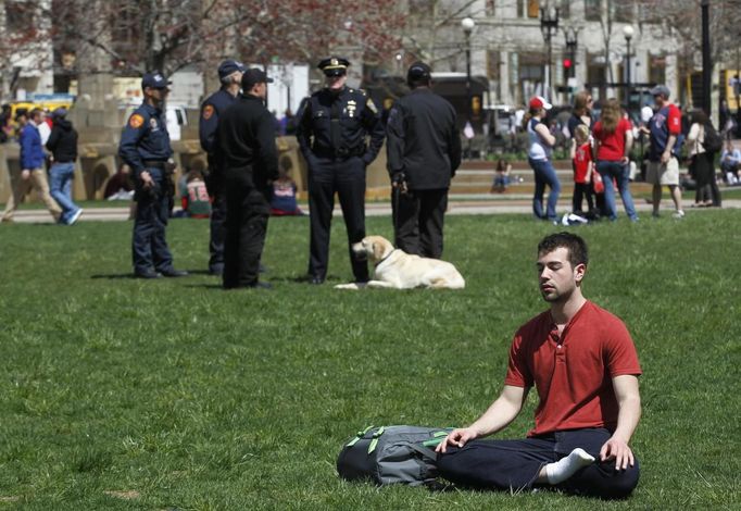 A man meditates in Copley Square Park as police officers congregate behind him after Boylston Street reopened to the public for the first time since the Boston Marathon bombings in Boston, Massachusetts April 24, 2013. REUTERS/Jessica Rinaldi (UNITED STATES - Tags: CRIME LAW CIVIL UNREST) Published: Dub. 24, 2013, 7:08 odp.