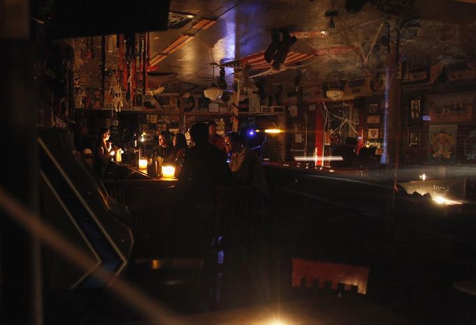 People sit in a bar lit by candlelight in the Lower East Village in the aftermath of Hurricane Sandy in New York October 31, 2012. New York City and the sodden U.S. Northeast began an arduous journey back to normal on Wednesday after mammoth storm Sandy killed at least 64 people in a rampage that swamped coastal cities and cut power to millions. REUTERS/Carlo Allegri (UNITED STATES - Tags: SOCIETY ENVIRONMENT DISASTER FOOD) Published: Lis. 1, 2012, 3:52 dop.