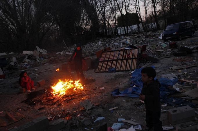 Israel Duval (R) and his cousin Desiree feed debris from his grandfather's home to a bonfire at the Spanish gypsy settlement of Puerta de Hierro outside Madrid February 15, 2012. Fifty-four families have been living in Puerta de Hierro, on the banks of the Manzanares river for over 50 years. Since the summer of 2010, the community has been subject to evictions on the grounds that the dwellings are illegal. Families whose houses have been demolished, move in with relatives whose houses still remain while the debris keeps piling up around them as more demolitions take place. Picture taken February 15, 2012. REUTERS/Susana Vera (SPAIN - Tags: SOCIETY) ATTENTION EDITORS - PICTURE 28 OF 31 FOR PACKAGE 'GYPSY SITE DEMOLISHED' SEARCH 'GYPSY SITE' FOR ALL IMAGES Published: Lis. 5, 2012, 4:12 odp.