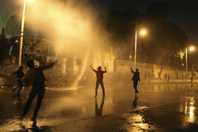 Protesters opposing Egyptian President Mohamed Mursi and the Muslim Brotherhood chant anti-government slogans while police spray water on them from inside the Presidential Palace, as some of the protesters try to break through one of the gates of the palace, in Cairo February 11, 2013. Protesters demanding the departure of Mursi clashed with police outside his palace on Monday on the second anniversary of the overthrow of veteran autocrat Hosni Mubarak. Dozens of youths threw rocks at the Ettihadiya palace after a peaceful march by thousands of demonstrators who accused Mursi's conservative Muslim Brotherhood of hijacking Egypt's democratic revolution and seeking to monopolise power. REUTERS/Asmaa Waguih (EGYPT - Tags: POLITICS CIVIL UNREST) Published: Úno. 11, 2013, 7:40 odp.