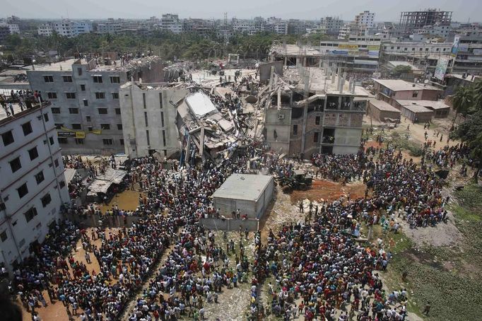 Crowds gather at the collapsed Rana Plaza building as people rescue garment workers trapped in the rubble, in Savar, 30 km (19 miles) outside Dhaka April 24, 2013. The eight-storey block housing garment factories and a shopping centre collapsed on the outskirts of the Bangladeshi capital on Wednesday, killing at least 25 people and injuring more than 500, the Ntv television news channel reported. REUTERS/Andrew Biraj (BANGLADESH - Tags: DISASTER BUSINESS EMPLOYMENT) Published: Dub. 24, 2013, 8:04 dop.