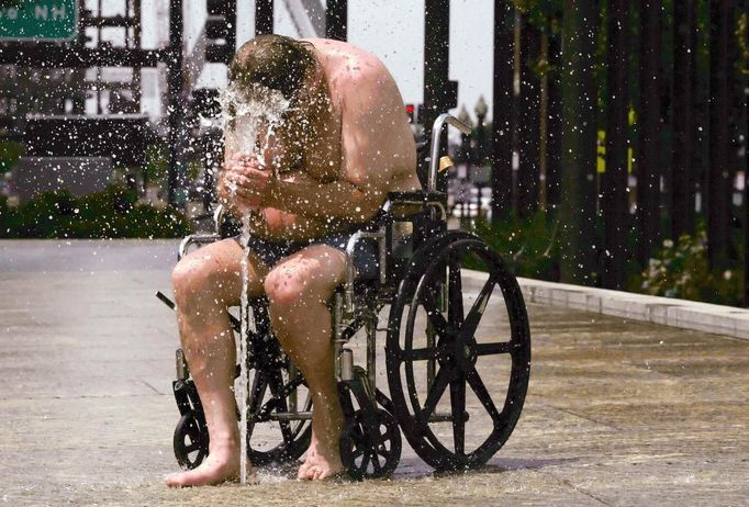 Jim Pearmain, sitting in a wheelchair, cools off in a fountain on the Rose Kennedy Greenway on a hot summer day in Boston, Massachusetts June 21, 2012. A heat wave blanketed the U.S. Mid-Alantic and Northeast Thursday, sparking brownouts in New York City and forcing utilities across the region to ask customers to conserve electricity. REUTERS/Brian Snyder (UNITED STATES - Tags: ENVIRONMENT ENERGY SOCIETY) Published: Čer. 21, 2012, 7:05 odp.