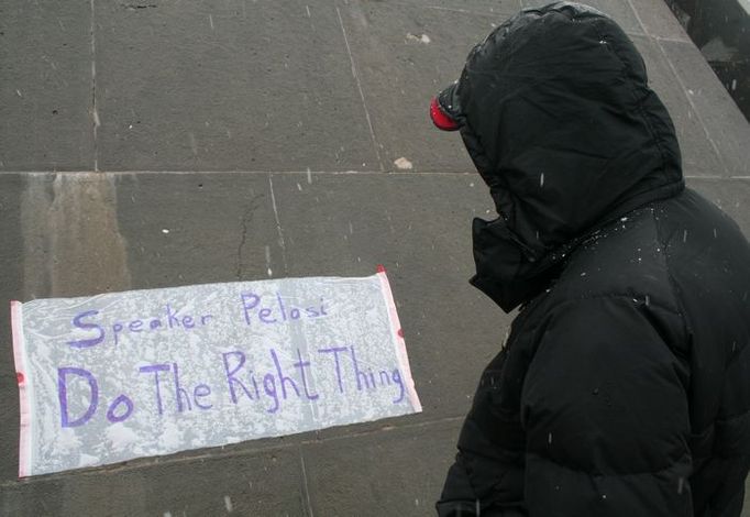 Muž si prohlíží plakát, který vyzývá Nancy Pelosiovou, šéfku Sněmovny reprezentantů, aby "udělala správnou věc" a pomohla prosadit uznání genocidy v americké sněmovně.