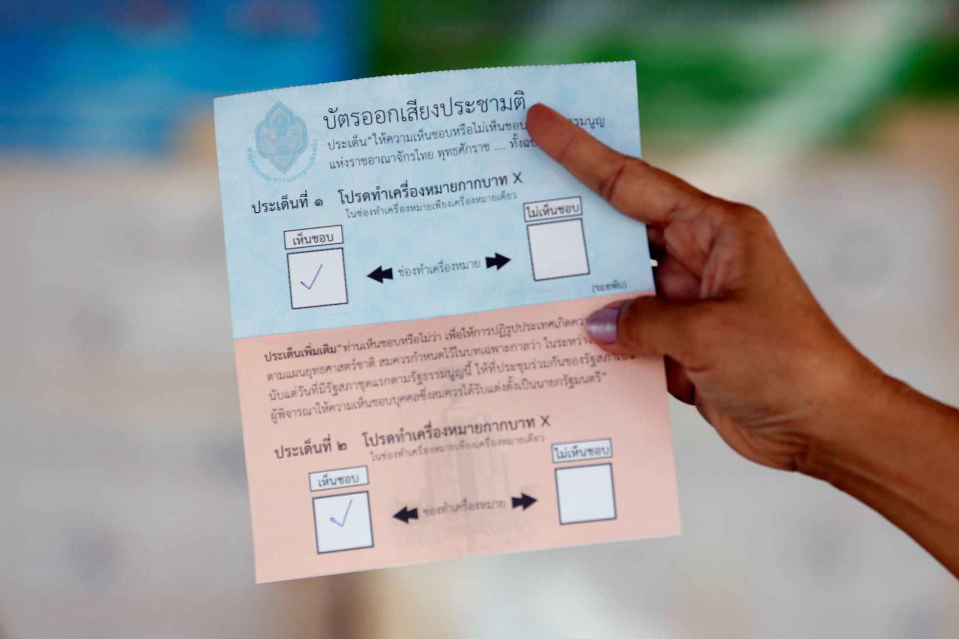 An election commission official displays a ballot paper to the media while counting votes during a constitutional referendum vote at a polling station in Bangkok