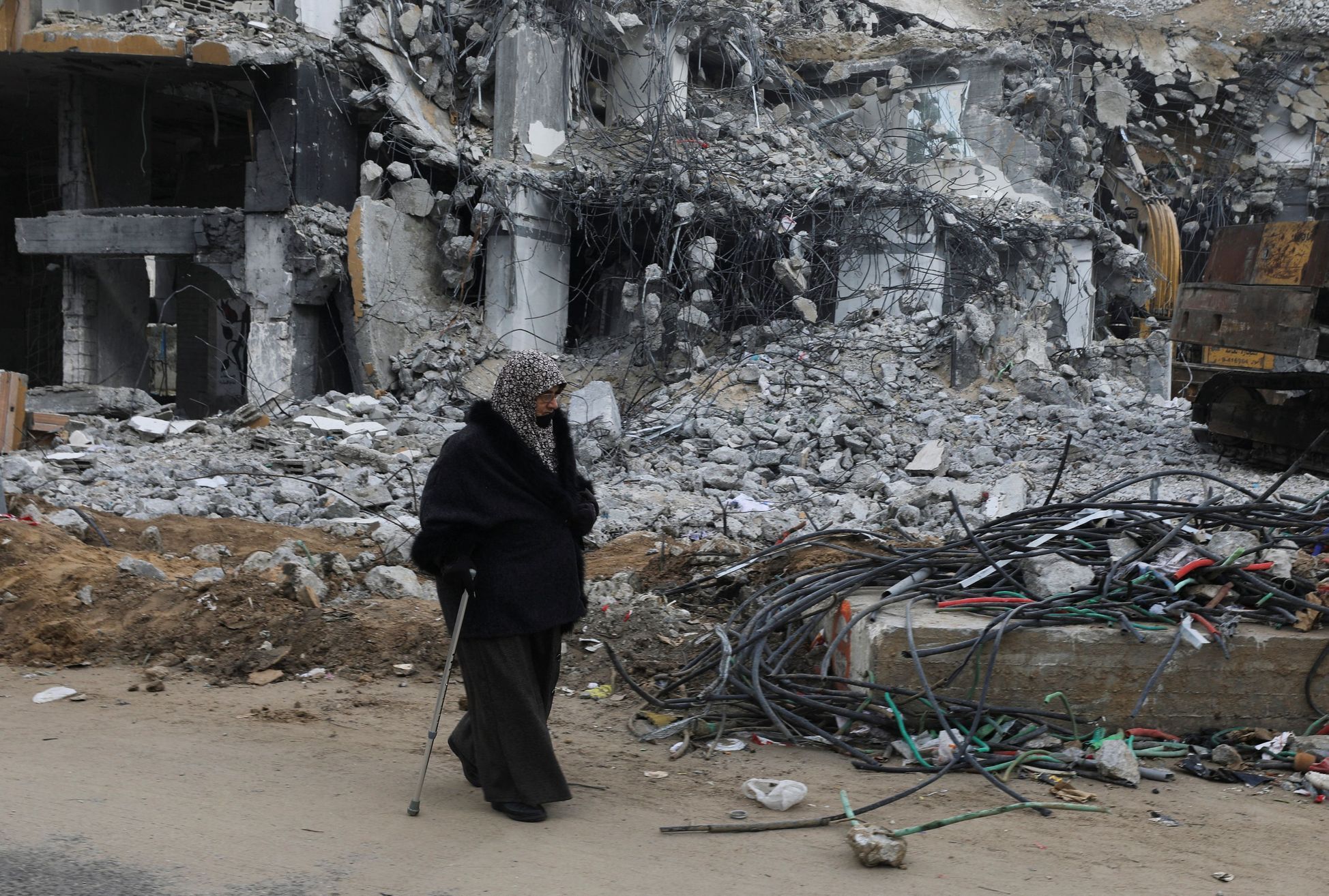 Žena v Palestině prochází kolem trosek budovy, kterou v Gaze zasáhl izraelský nálet.