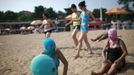 Women, wearing nylon masks, rest on the shore as youths walk past them during their visit to a beach in Qingdao, Shandong province July 6, 2012. The mask, which was invented by a woman about seven years ago, is used to block the sun's rays. The mask is under mass production and is on sale at local swimwear stores. REUTERS/Aly Song (CHINA - Tags: SOCIETY ENVIRONMENT TRAVEL) Published: Čec. 6, 2012, 4:19 odp.