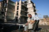 Muž plní kanystr před zničeným panelovým domem v Grozném.