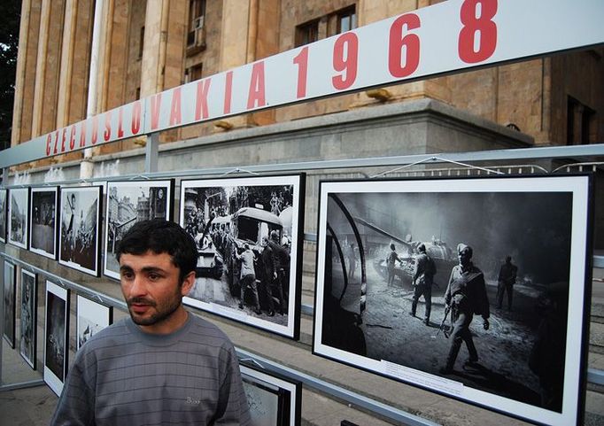 Muž stojí u panelu s fotografiemi zachycujícími napadení Československa v roce 1968. Fotografie byly umístěny před hlavní vchod gruzínského parlamentu.