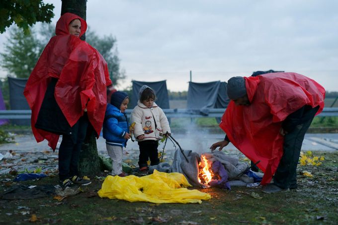 Rodina běženců se zahřívá u ohně ve slovinském městě Trnovec.