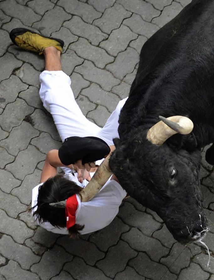 A runner is dragged by his scarf by a Dolores Aguirre fighting bull at the entrance to the bullring during the first running of the bulls of the San Fermin festival in Pamplona July 7, 2012. One person was gored and four others injured in a run that lasted two minutes and fifty-two seconds, according to local media. REUTERS/Vincent West (SPAIN - Tags: ANIMALS SOCIETY TPX IMAGES OF THE DAY) Published: Čec. 7, 2012, 7:51 dop.