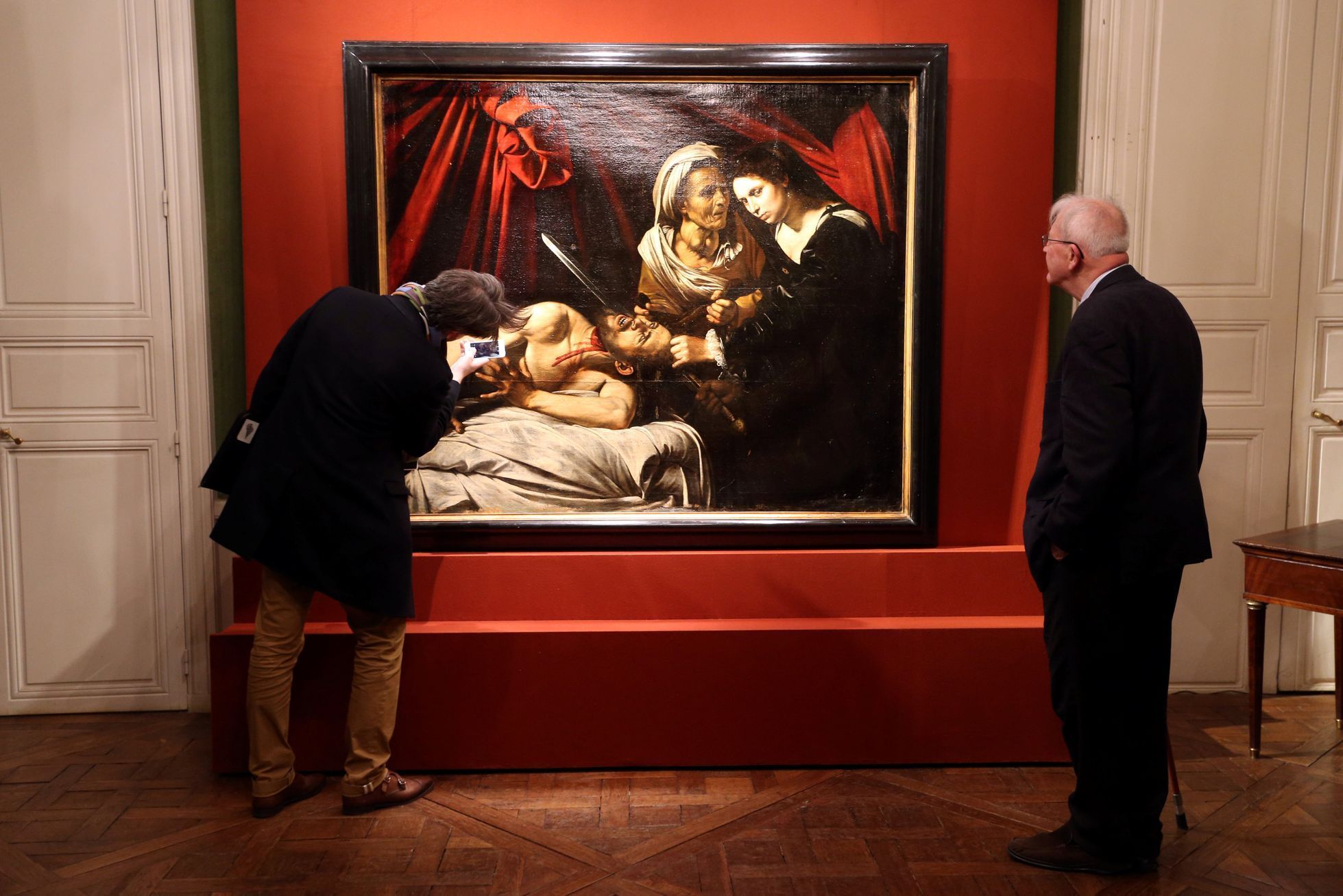 Visitors looks at a painting entitled &quot;Judith Beheading Holofernes&quot; during its presentation in Paris