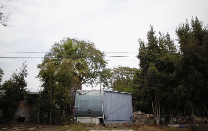 A trailer surrounded by trees is seen in Village Trailer Park in Santa Monica, California, July 13, 2012. Developer Marc Luzzatto wants to relocate residents from the trailer park to make way for nearly 500 residences, office space, stores, cafes and yoga studios, close to where a light rail line is being built to connect downtown Los Angeles to the ocean. Village Trailer Park was built in 1951, and 90 percent of its residents are elderly, disabled or both, according to the Legal Aid Society. Many have lived there for decades in old trailers which they bought. The property is valued at as much as $30 million, according the LA Times. REUTERS/Lucy Nicholson (UNITED STATES - Tags: REAL ESTATE BUSINESS SOCIETY POLITICS) Published: Čec. 14, 2012, 7:37 dop.