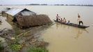 Flood-affected local residents move to safer places on a boat next to their damaged huts after heavy rains at Jajimukh village in the northeastern Indian state of Assam June 27, 2012. Incessant heavy rains in northeast India have caused massive flooding and landslides, killing at least 10 people, local media reported on Wednesday. REUTERS/Stringer (INDIA - Tags: ENVIRONMENT DISASTER) Published: Čer. 27, 2012, 5:46 odp.