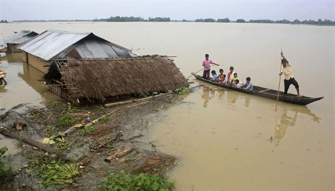 Flood-affected local residents move to safer places on a boat next to their damaged huts after heavy rains at Jajimukh village in the northeastern Indian state of Assam June 27, 2012. Incessant heavy rains in northeast India have caused massive flooding and landslides, killing at least 10 people, local media reported on Wednesday. REUTERS/Stringer (INDIA - Tags: ENVIRONMENT DISASTER) Published: Čer. 27, 2012, 5:46 odp.