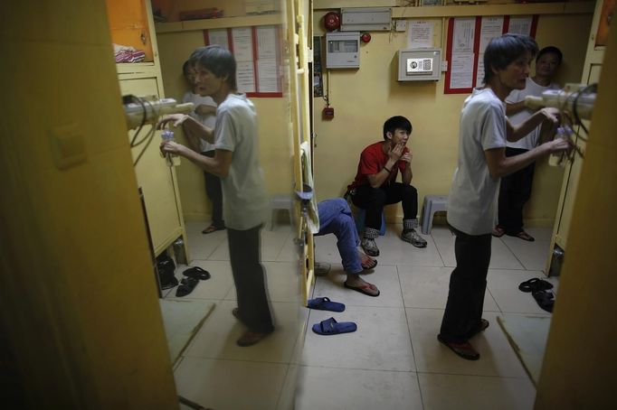 People sit in a common area between wooden boxes they use for living in Hong Kong October 9, 2012. In Hong Kong's middle-class residential area, short distance from its shopping and financial districts, 24 people live in these wooden boxes, or "coffin homes", packed in a single apartment of little over 50 square meters. Its residents pay 1450 Hong Kong dollars ($180) for their living space built of wooden panels of 2 meters by 70 cm. To maximize income from the rent in central Hong Kong landlords build "coffin homes", nicknamed due to their resemblance to real coffins. Space has always been at a premium in Hong Kong where developers plant high-rises on every available inch. REUTERS/Damir Sagolj (CHINA - Tags: SOCIETY REAL ESTATE BUSINESS) Published: Říj. 9, 2012, 2:01 odp.