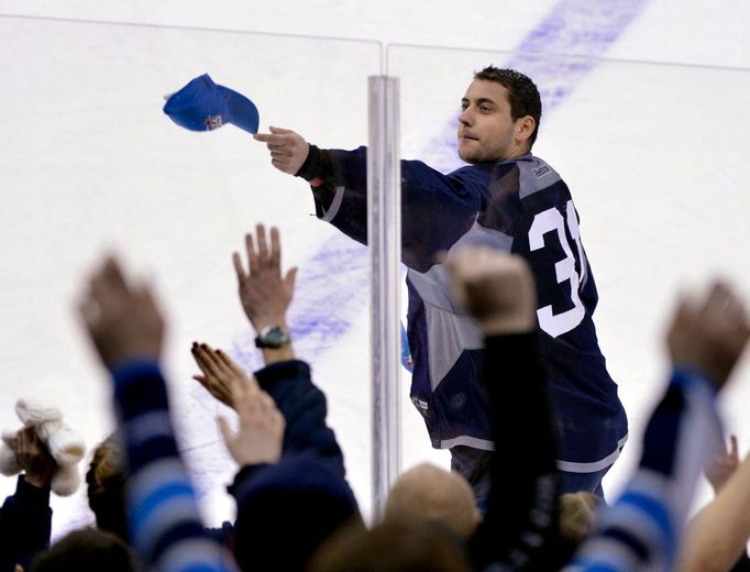 Brankář Ondřej Pavelec během tréninku Winnipegu hází kšiltovku fanouškům