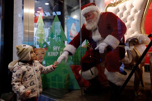 Tříletá dívka zdraví Santa Clause ve výloze obchodu v Bostonu.