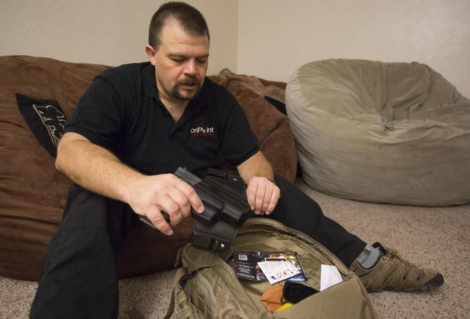 Phil Burns pulls a gun from his backpack full of survival supplies at his home in American Fork, Utah, December 14, 2012. While most "preppers" discount the Mayan calendar prophecy, many are preparing to be self-sufficient for threats like nuclear war, natural disaster, famine and economic collapse. Picture taken December 14, 2012. REUTERS/Jim Urquhart (UNITED STATES - Tags: SOCIETY) Published: Pro. 18, 2012, 5:23 odp.