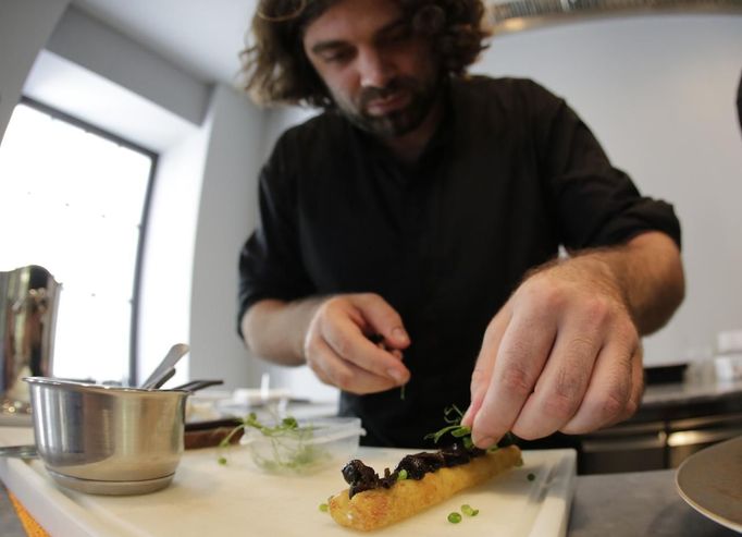 Austrian chef Konstantin Filippou prepares a snail dish in his gourmet restaurant in Vienna July 12, 2013. Andreas Gugumuck owns Vienna's largest snail farm, exporting snails, snail-caviar and snail-liver all over the world. The gourmet snails are processed using old traditional cooking techniques and some are sold locally to Austrian gourmet restaurants. Picture taken July 12, 2013. REUTERS/Leonhard Foeger (AUSTRIA - Tags: ANIMALS FOOD SOCIETY) Published: Čec. 16, 2013, 11:14 dop.