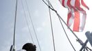 U.S. Navy quarter master Krystal Jones raise a flag on the USS Wasp as the amphibious assault ship enters into New York Harbor for Fleet Week May 23, 2012. REUTERS/Keith Bedford (UNITED STATES - Tags: MILITARY SOCIETY MARITIME) Published: Kvě. 23, 2012, 8:25 odp.