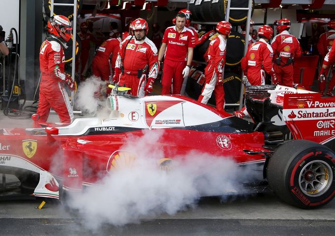 Ferrari F1 driver Kimi Raikkonenin (L) walks away from his car after it caught fire in pit lane during the Australian Formula One Grand Prix in Melbourne. REUTERS/Brandon