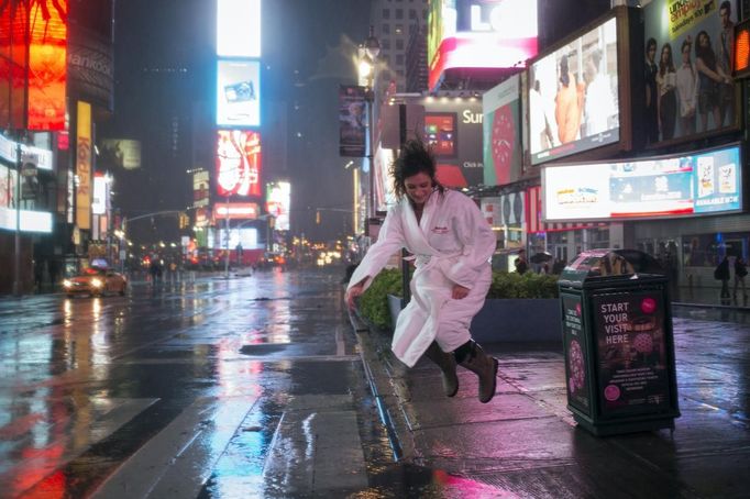 A woman in a bathrobe jumps into a puddle of rain water while visiting Times Square in New York October 29, 2012. As Hurricane Sandy aimed straight for them, promising to hammer the place they live with lashing winds and extensive flooding, New Yorkers seemed to be all about nonchalance on Monday morning - an attitude that didn't last into the afternoon. REUTERS/Adrees Latif (UNITES STATES - Tags: ENVIRONMENT DISASTER SOCIETY) Published: Říj. 30, 2012, 12:46 dop.