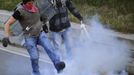 Two coal miners kick a smoke bomb during confrontations with the riot Civil Guard after setting an incendiary device to a barricade near highway A-66 in Vega del Rey, near Oviedo, northern Spain, June 4, 2012. Spain's economy contracted for the second time since late 2009 and four years of stagnation and recession have pushed unemployment above 24 percent, the highest rate in the European. REUTERS/Eloy Alonso (SPAIN - Tags: POLITICS CIVIL UNREST BUSINESS EMPLOYMENT) Published: Čer. 4, 2012, 10:53 dop.