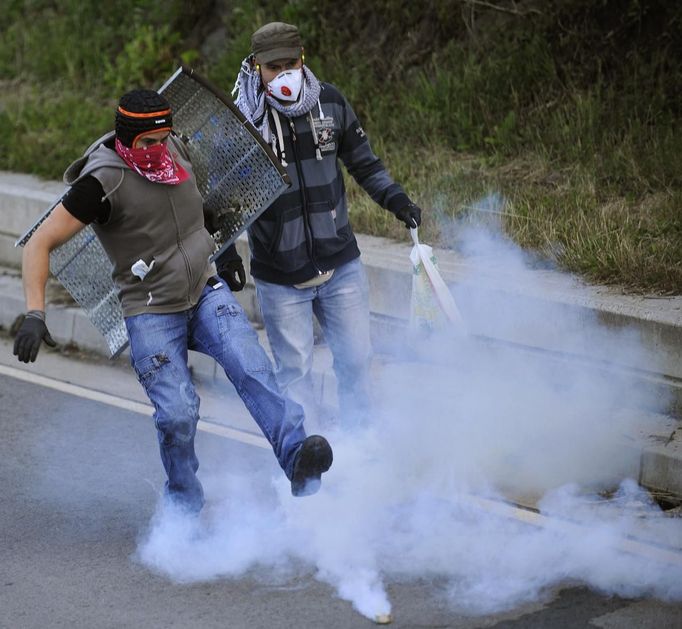 Two coal miners kick a smoke bomb during confrontations with the riot Civil Guard after setting an incendiary device to a barricade near highway A-66 in Vega del Rey, near Oviedo, northern Spain, June 4, 2012. Spain's economy contracted for the second time since late 2009 and four years of stagnation and recession have pushed unemployment above 24 percent, the highest rate in the European. REUTERS/Eloy Alonso (SPAIN - Tags: POLITICS CIVIL UNREST BUSINESS EMPLOYMENT) Published: Čer. 4, 2012, 10:53 dop.