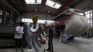 Two workers paint a hand for a bus at a factory hall in Prague as they work on artist David Cerny's project to transform a London bus into a robotic sculpture May 22, 2012. The bus, which Cerny hopes could become an unofficial mascot of the London 2012 Olympic Games, does push-ups with the help of an engine powering a pair of robotic arms and the motion is accompanied by a recording of sounds evoking tough physical effort. It will be parked outside the Czech Olympic headquarters in London for the duration of the Games. Picture taken May 22, 2012. REUTERS/Petr Josek (CZECH REPUBLIC - Tags: SOCIETY SPORT OLYMPICS TRANSPORT) Published: Čec. 22, 2012, 5:52 odp.