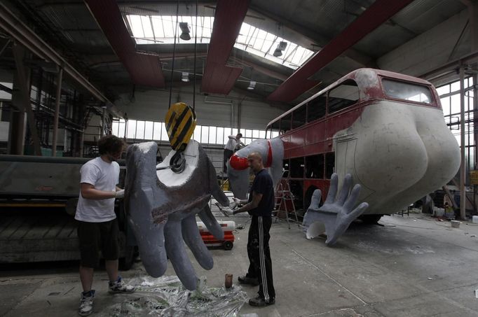 Two workers paint a hand for a bus at a factory hall in Prague as they work on artist David Cerny's project to transform a London bus into a robotic sculpture May 22, 2012. The bus, which Cerny hopes could become an unofficial mascot of the London 2012 Olympic Games, does push-ups with the help of an engine powering a pair of robotic arms and the motion is accompanied by a recording of sounds evoking tough physical effort. It will be parked outside the Czech Olympic headquarters in London for the duration of the Games. Picture taken May 22, 2012. REUTERS/Petr Josek (CZECH REPUBLIC - Tags: SOCIETY SPORT OLYMPICS TRANSPORT) Published: Čec. 22, 2012, 5:52 odp.