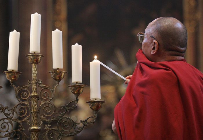 Dalajlama zapaluje svíce v kostele sv. Salvátora