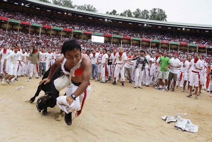 REFILE - QUALITY REPEAT A Japanese runner is tossed by a wild cow during festivities in the bullring following the third running of the bulls in Pamplona July 9, 2012. Three people, two from Britain and one from the U.S. were gored by Fugado (Runaway), a 545 kg (1,199 pounds) bull that broke from the pack after falling in Santo Domingo in a run that lasted three minutes and thirty-eight seconds. REUTERS/Joseba Etxaburu (SPAIN - Tags: ANIMALS SOCIETY TPX IMAGES OF THE DAY) Published: Čec. 9, 2012, 10:02 dop.