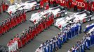 Audi (red) and Toyota teams wait near their cars as the French national anthem plays, just before the Le Mans 24-hour sportscar race in central France June 22, 2013. REUT