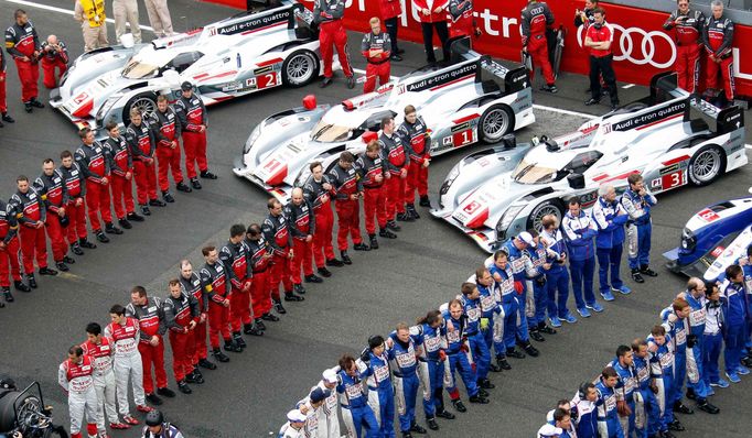 Audi (red) and Toyota teams wait near their cars as the French national anthem plays, just before the Le Mans 24-hour sportscar race in central France June 22, 2013. REUT