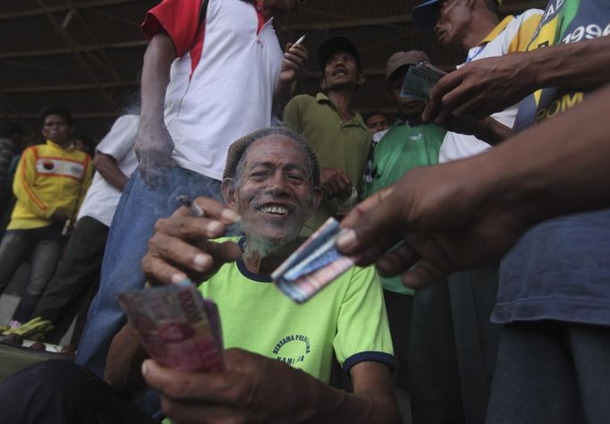 A gambler collects his money after a win on a horse race at a racetrack outside Bima, November 17, 2012. Dozens of child jockeys, some as young as eight-years-old take part in the races. Involving nearly 600 horses they take place around a dusty, oval track of 1,400 meters (nearly one mile). The reward, for the winner is a handful of cash for his family, and glory for the jockey. The grand prize is one million rupiah ($100). Those who win their groups get two cows. The chairman of the races' organising team, Hajji Sukri, denies that there is any danger to the children saying they are all skilful riders and none has been killed or seriously hurt. Picture taken November 17, 2012. REUTERS/Beawiharta (INDONESIA - Tags: SPORT SOCIETY) ATTENTION EDITORS: PICTURE 5 of 25 FOR PACKAGE 'BETTING ON CHILD JOCKEYS' Published: Lis. 24, 2012, 9:15 dop.