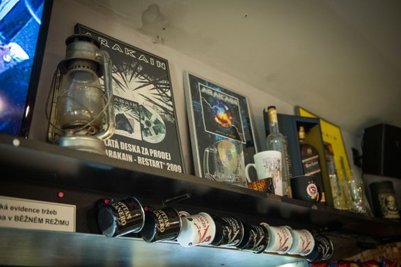 Zlaté desky kapely jsou rozestavěné nad barem vedle lahví s alkoholem.