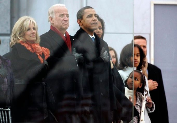 Rodiny Baracka Obamy a jeho viceprezidenta Joea Bidena za neprůstřelným sklem. Ruka na srdci značí, že se právě hraje hymna USA.