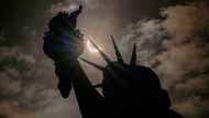 Socha Svobody při částečném zatmění Slunce, kdy Měsíc částečně zakrývá Slunce, na ostrově Liberty Island v New Yorku.