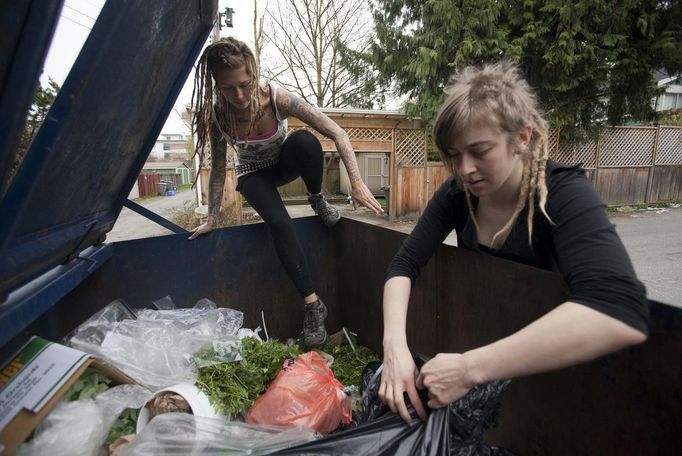 May Wollf, (L), 28, a practising 'freegan', climbs into a dumpster while Robin Pickell tears open a garbage bag in an alley behind Commercial Drive in Vancouver, British Columbia April 10, 2012. A 'Freegan' is someone who gathers edible food from the garbage bins of grocery stores or food stands that would otherwise have been thrown away. Freegans aim to spend little or no money purchasing food and other goods, not through financial need but to try to address issues of over-consumption and excess. Picture taken April 10, 2012. REUTERS/Ben Nelms (CANADA - Tags: SOCIETY) ATTENTION EDITORS PICTURE 02 OF 21 FOR PACKAGE 'DUMPSTER DIVING FOR FOOD' Published: Kvě. 15, 2012, 11:57 dop.