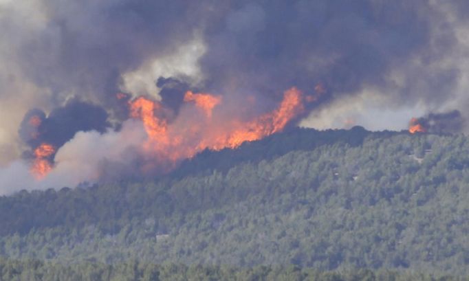 A wall of flames makes its way through trees and brush prompting fire officials to order the evacuation of Fairview, Utah as the Wood Hollow fire approaches the town June 26, 2012. Authorities said a body was found in the ashes of a house charred by the fast-moving fire, marking the first fatality in a blaze that already has scorched more than 39,000 acres. Fresh evacuations were ordered there on Tuesday. The blaze had already burned an estimated 30 homes and killed 75 sheep between the rural communities of Fountain Green and Indianola. REUTERS/George Frey (UNITED STATES - Tags: ENVIRONMENT DISASTER) Published: Čer. 27, 2012, 1:05 dop.