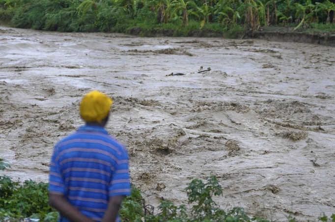 A man watches heavy rains from Hurricane Sandy cause the Croix de Mission river to swell to levels that threaten to flood the homes along its bank and nearby areas, in Port-au-Prince October 25, 2012. According to media reports Hurricane Sandy has claimed one life in Haiti. REUTERS/Swoan Parker (HAITI - Tags: DISASTER ENVIRONMENT) Published: Říj. 25, 2012, 11:32 odp.