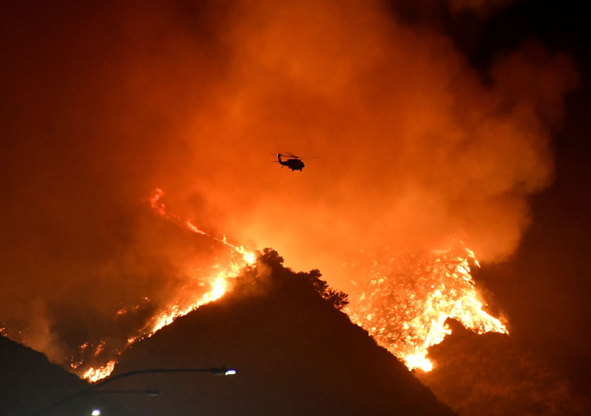 A firefighting helicopter flies over the Getty Fire as it burns in the hills west of the 405 freeway in the hills of West Los Angeles, California
